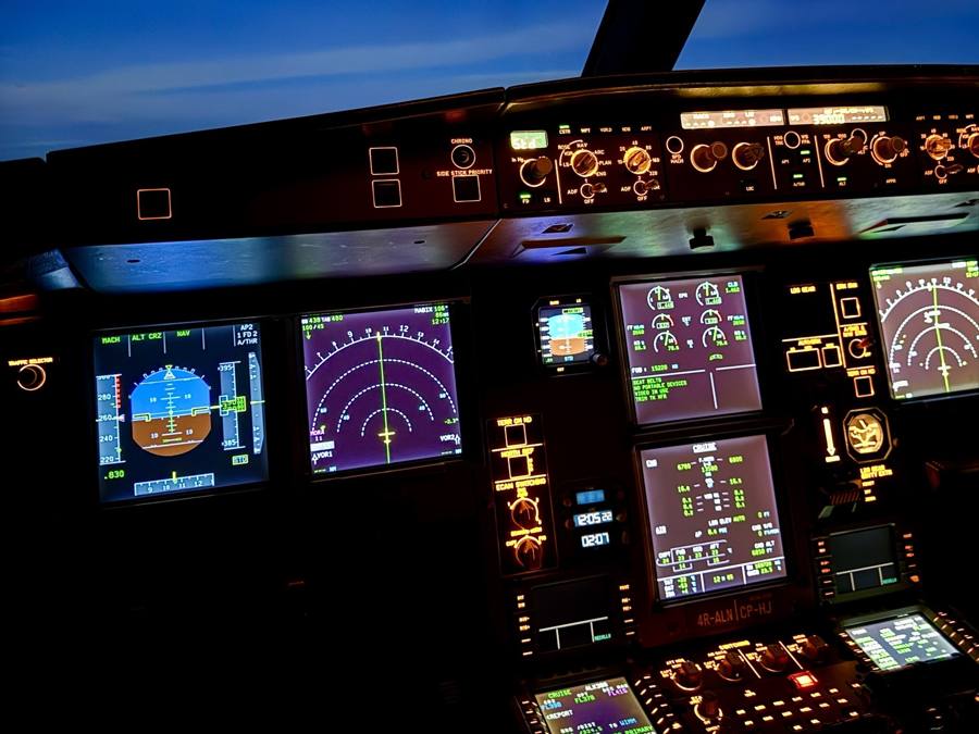 An airline flight deck at dusk, instruments lit, during cruise